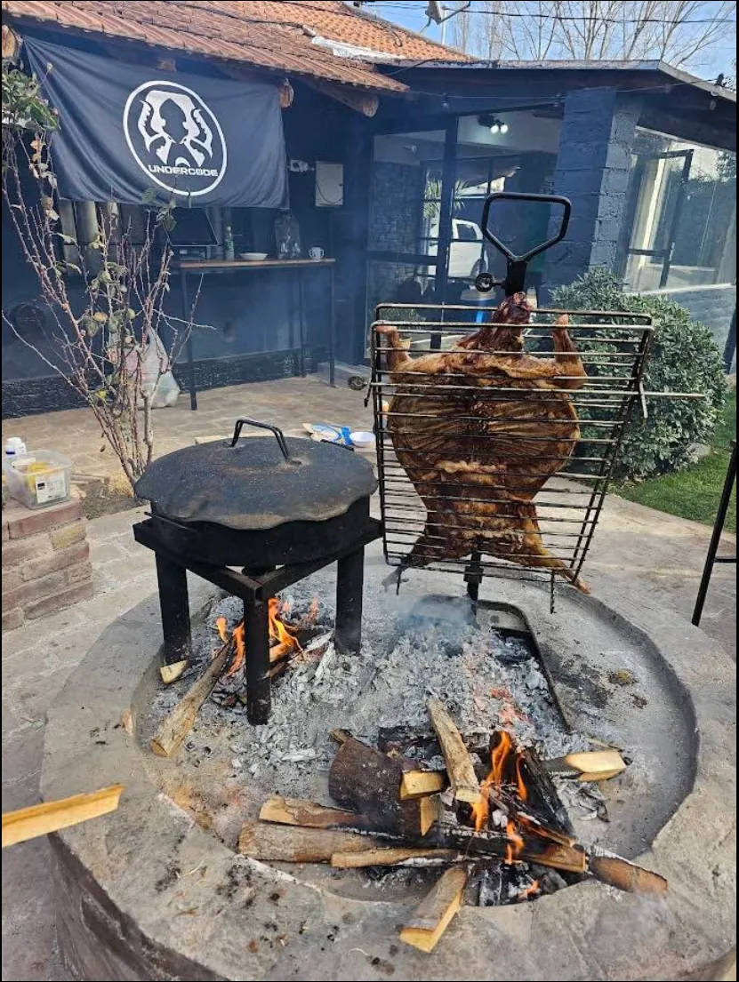 Carne cocinándose en asador vertical sobre el fuego